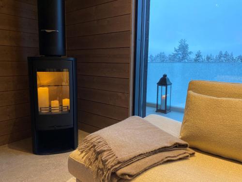 a room with a fireplace with a chair and a window at Villa Primus in Ruka