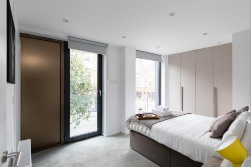 homely - Central London Camden Penthouse Apartment في لندن: غرفة نوم بسرير كبير ونافذة كبيرة