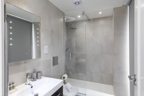 La salle de bains est pourvue d'un lavabo blanc et d'une douche. dans l'établissement homely - Central London Camden Penthouse Apartment, à Londres