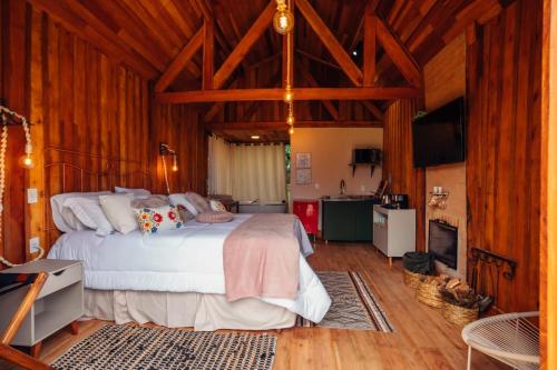 a bedroom with a large bed and a kitchen at Montanha Home in Monte Verde