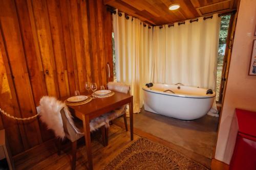 a bathroom with a bath tub and a table and a tableablish at Montanha Home in Monte Verde