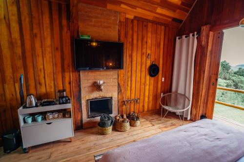 a bedroom with wooden walls and a fireplace and a bed at Montanha Home in Monte Verde