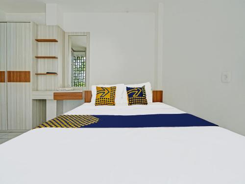 a bedroom with a large bed with yellow and blue pillows at SUPER OYO 2190 Alamanda 7 Syariah in Bandung