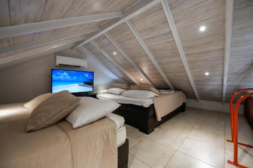 a bedroom with two beds and a tv in a attic at Boutique Hotel Swiss Paradise Aruba Villas and Suites in Palm-Eagle Beach