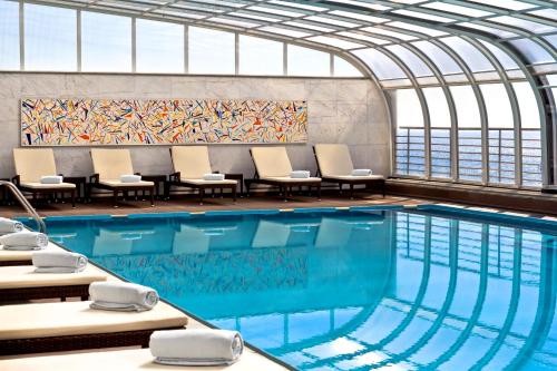 uma piscina num edifício com cadeiras e um quadro em SANA Sesimbra Hotel em Sesimbra