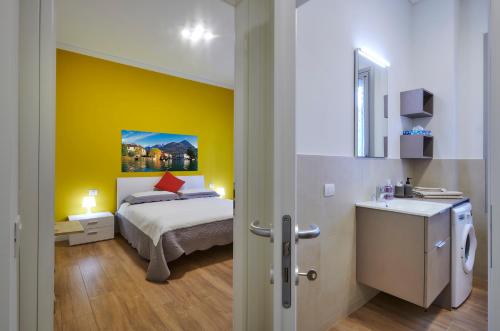 1 dormitorio con cama y pared amarilla en Lecco Lake Apartments Villa Liberty, en Lecco