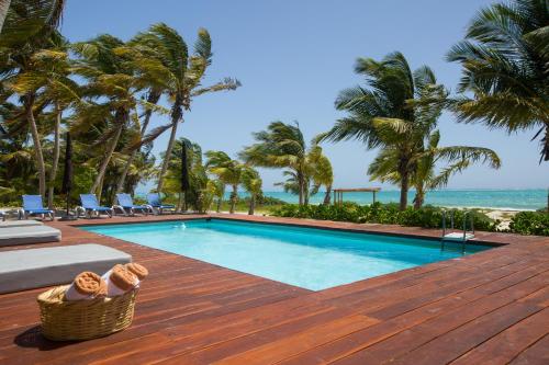 a swimming pool on a wooden deck next to the ocean at Casa Camara in Sian ka'an in Punta Allen