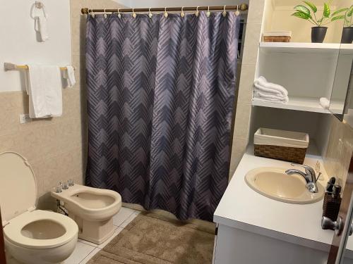 a bathroom with a toilet and a shower curtain at The Villas of John St. Rose in Christiansted