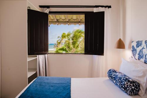 1 dormitorio con ventana y vistas al océano en Pousada Aldeola by Slaviero Hotéis, en Baixio