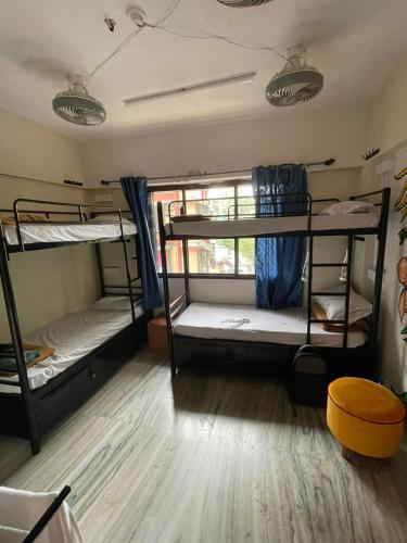 a room with three bunk beds and a wooden floor at Krazy Solo Hostel in Mumbai