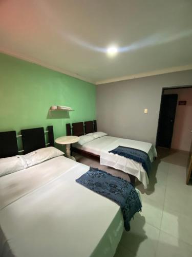 a room with three beds and a table in it at Hotel Napoles Valledupar in Valledupar