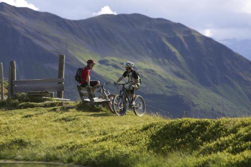 two people riding bikes on a grassy hill at Pension Riedlsperger in Saalbach Hinterglemm