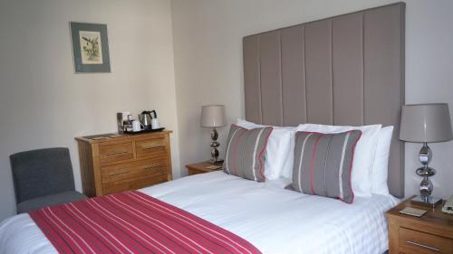 a bedroom with a white bed with two pillows at The Lawn Guest House Gatwick in Horley