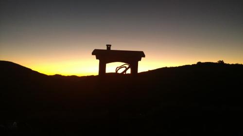 a cross on top of a hill at sunset at Montanha Home in Monte Verde