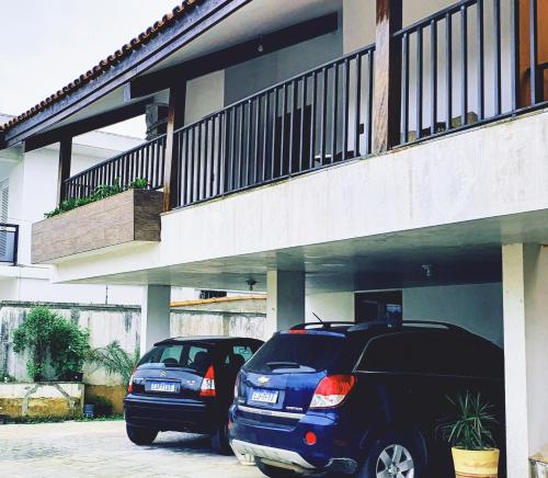 two cars parked in a parking lot under a building at Royal-inn SPA & Pousada in Itanhaém