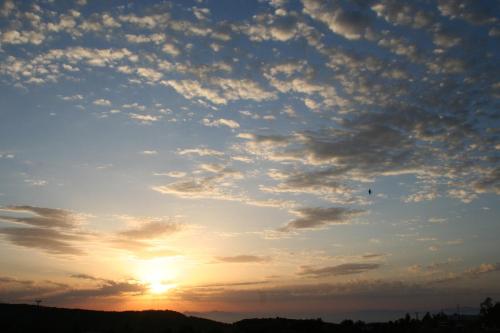 a cloudy sky at sunset with a bird in the sky at Ataviros Hotel in Émbonas
