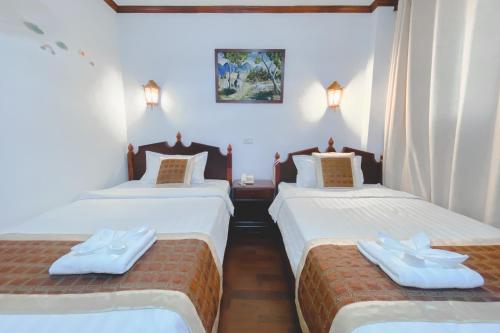 Habitación con 2 camas, sábanas blancas y toallas. en Khampiane1 Hotel en Ban Nongdouang