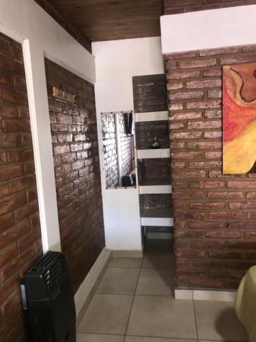 Habitación con pared de ladrillo y espejo. en Hospedaje “Las Lias” en Malargüe