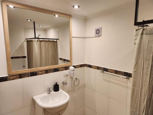 a white bathroom with a sink and a mirror at Andes Departamentos in El Bolsón