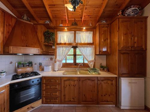 a kitchen with wooden cabinets and a sink and a stove at Kapilio Cottage House in Kapilio