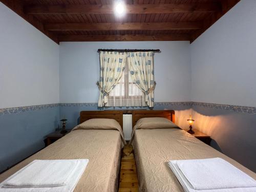 two beds in a room with a window at Kapilio Cottage House in Kapilio