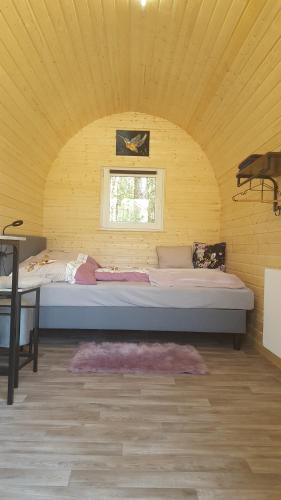 Cama grande en habitación amarilla con ventana en Glamping Pod im Wald, en Nordholz