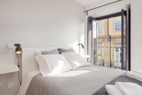 a white bedroom with a bed and a window at Be In Oporto in Porto