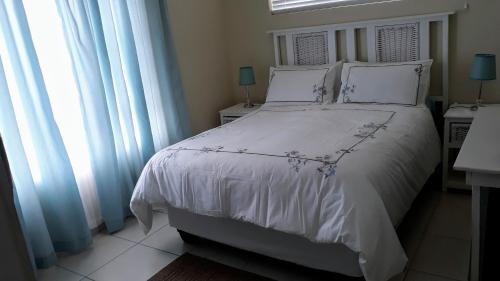1 dormitorio con 1 cama blanca con sábanas blancas y ventanas en Potgieter's View, en Reebok