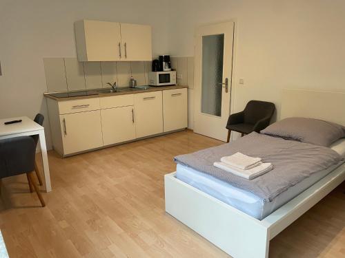 City Apart Düss في دوسلدورف: غرفة نوم صغيرة بها سرير ومطبخ