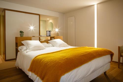 a bedroom with a large bed with a yellow blanket on it at Hotel Echaurren Relais & Châteaux in Ezcaray
