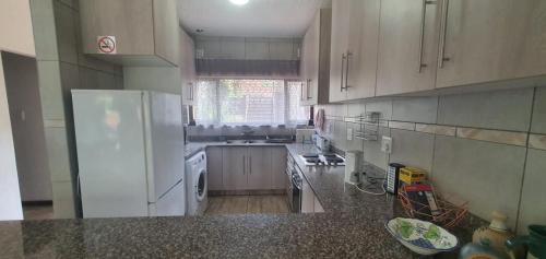 a kitchen with a white refrigerator and a sink at Beach Break Holiday Flat in Port Shepstone