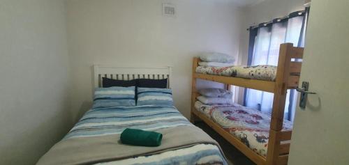 a bedroom with two bunk beds and a window at Beach Break Holiday Flat in Port Shepstone