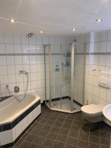 La salle de bains est pourvue d'une douche, d'une baignoire et de toilettes. dans l'établissement Ferienwohnung Emma, à Olsberg