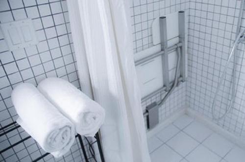La salle de bains est pourvue de murs carrelés blancs et de serviettes blanches. dans l'établissement AIRPORT HOTEL Entebbe, à Entebbe