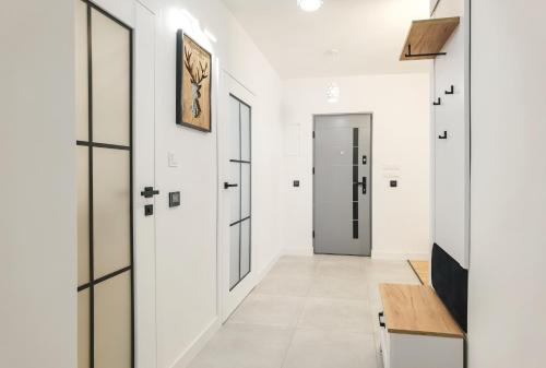 korytarz z białymi ścianami i drzwiami oraz drewnianym stołem w obiekcie Apartament Green Forest w mieście Duszniki Zdrój