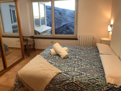 a bedroom with a bed with two pillows and two windows at Sierra Nevada Nice Home & Chimenea in Sierra Nevada
