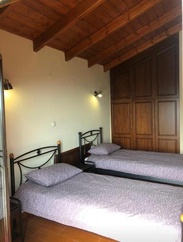 two beds in a room with wooden ceilings at Koukouvistahouse in Kaloskopí