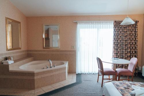 La salle de bains est pourvue d'une baignoire et d'une table avec des chaises. dans l'établissement Skaneateles Suites, à Skaneateles