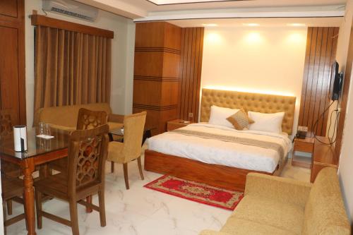 a bedroom with a bed and a desk and a table at Hotel Blue Moon in Chittagong