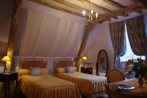 a bedroom with two beds and a chandelier at Domaine De Chatenay - Le Mans in Saint-Saturnin