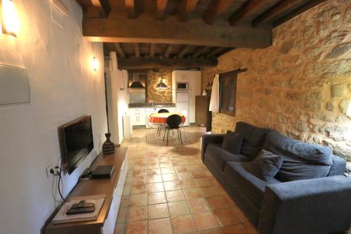 a living room with a couch and a tv at Apartamentos Rurales SPA Casa De Los Escudos in Valverde de la Vera