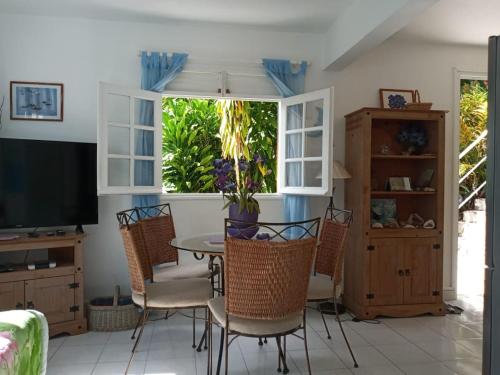 a dining room with a table and chairs and a television at Les Hauts de Terrasson in Les Abymes