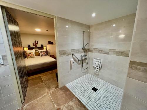 a bathroom with a shower and a bed in a room at Hotel Le Ranch in Brûlon