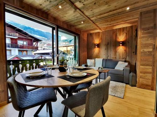 une table et des chaises dans une pièce avec une grande fenêtre dans l'établissement Studio rénové avec kitchenette, balcon et wifi - FR-1-598-84, aux Gets