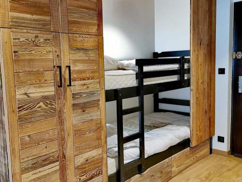 Cette chambre comprend 2 lits superposés et une porte en bois. dans l'établissement Studio rénové avec kitchenette, balcon et wifi - FR-1-598-84, aux Gets