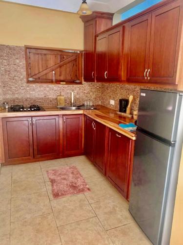 a kitchen with wooden cabinets and a stainless steel refrigerator at ORCHID RESORT Ltd in Guillet