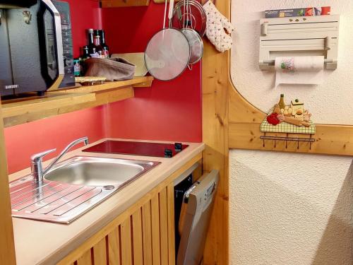 une petite cuisine avec un évier et un micro-ondes dans l'établissement Appartement cosy · Proche pistes · Balcon · 6 pers · Wifi - FR-1-346-326, à Arc 1800