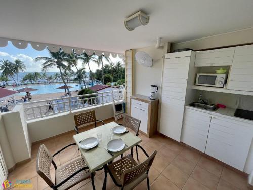 a kitchen with a table and chairs with a view of the beach at Studios Barbadine - Resorts Flats in Sainte-Anne