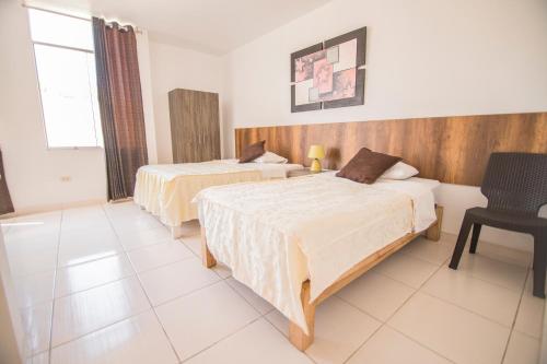 een hotelkamer met 2 bedden en een stoel bij Señorio Chiribaya in Ilo