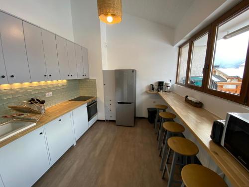 La cuisine est équipée d'un comptoir avec tabourets et d'un réfrigérateur. dans l'établissement Grand duplex rénové - 10 pers, 4 ch, 3 sdb, 80m2 terrasse - FR-1-546-10, à Les Deux Alpes